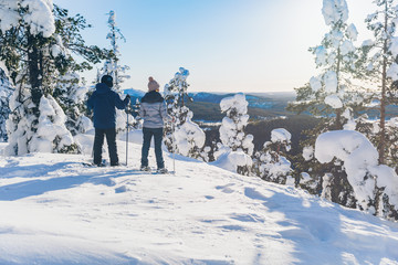 Travelers in the mountains walk on snowshoes at sunrise in winter nature, Finland