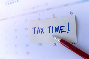 Tax time concept; Close Up of Tax Time written on the white paper note with a calendar.