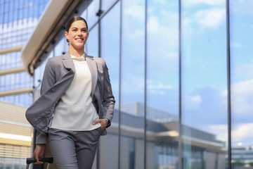 Portrait of successful business woman in suit looking away while walking outdoors.