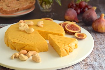 Homemade vegan cheese made from cashew nuts served with gluten free bread on wooden board