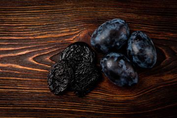 Fresh plum and prune on dark wooden background.