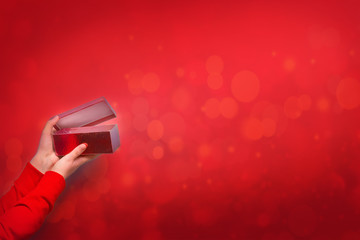 Woman holding open box with christmas or valentine's day present on red background

