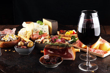 Italian antipasti wine snacks set. Cheese variety, Mediterranean olives, seafood salad, Prosciutto di Parma, tomatoes, anchovy and wine in glasses