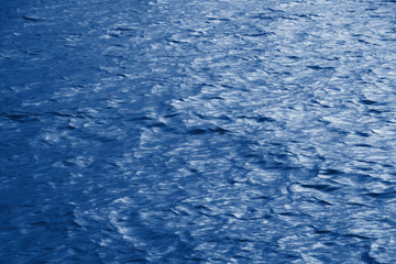 Classic blue sea water texture. Pool water with sun reflections. Trendy colour 2020 year. Classic blue background. Dark classic blue sea wave. Out focus. Color 2020.