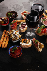 Appetizers table with italian antipasti snacks and wine in glasses. Brushetta or authentic traditional spanish tapas set, cheese variety