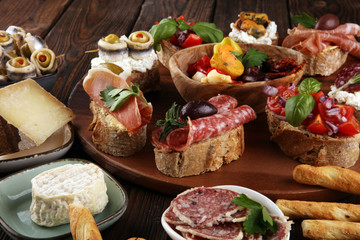 Appetizers table with italian antipasti snacks and wine in glasses. Brushetta or authentic traditional spanish tapas set, cheese variety