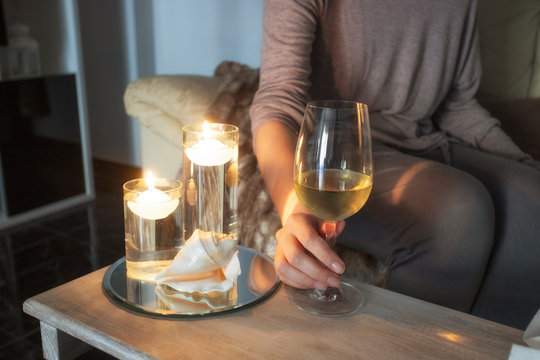 Woman  sitting in sofa and holding glass winein living room. Relax at cosy home concept.