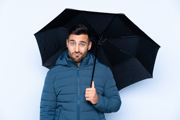 Man holding an umbrella over isolated background with sad expression