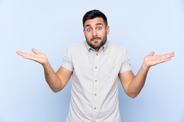 Young handsome man with beard over isolated blue background having doubts with confuse face expression