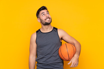 Handsome young basketball player man over isolated white wall looking up while smiling