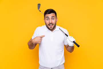 Golfer player man over isolated yellow background with surprise facial expression