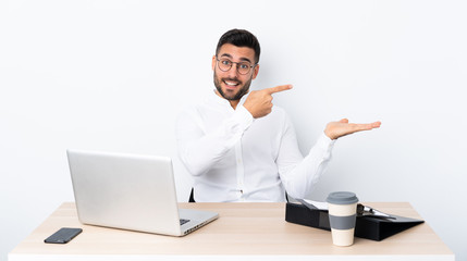 Young businessman in a workplace holding copyspace imaginary on the palm to insert an ad