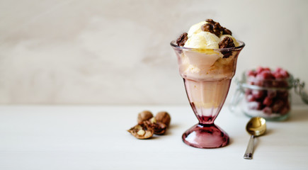Creamy ice cream with honey and walnuts. Served in a bowl with ice cream, garnished with walnuts and honey. On the table is a jar with dried strawberries, a spoon and a walnut.