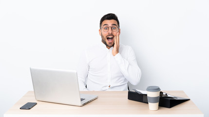 Young businessman in a workplace with surprise and shocked facial expression