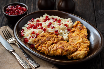 Turkey schnitzel, served with rice and pomegranate seeds.