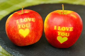 Two Red Apple with text I LOVE YOU in a black clay bowl on red background. I love you apple. Apple for Valentine's Day
