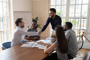 Smiling diverse male colleagues handshake at business briefing