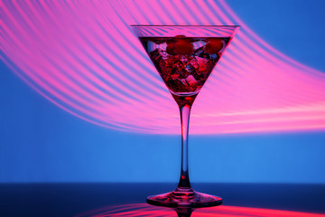 Glass of martini with ice shot in a long exposure in neon light