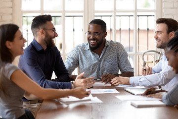 Smiling diverse millennial colleagues have fun at meeting