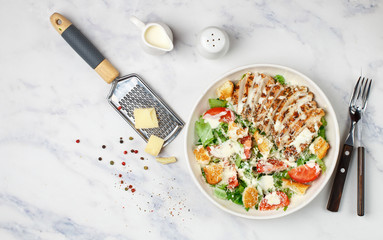 Healthy Grilled Chicken Caesar Salad with iceberg or lettuce, Cheese Parmesan, tomatoes, bread Croutons and gourmet sauce. Selective focus, top view and copy space