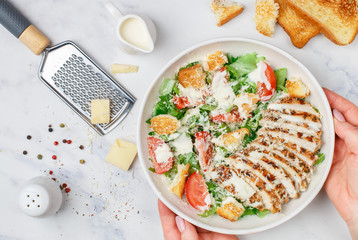 Healthy Grilled Chicken Caesar Salad with iceberg or lettuce, Cheese Parmesan, tomatoes, bread Croutons and gourmet sauce. Selective focus, top view and copy space