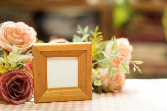 empty wooden picture frame placed on a pink and white grid pattern background flower decoration