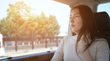 tired woman languishes from hot weather adjusting white sweater neck travelling by car in touristic...