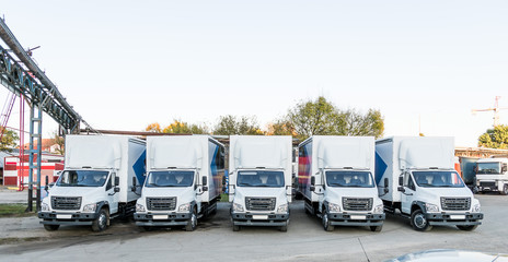Five white truckers in the parking lot are waiting for the next delivery of goods. The concept of a...