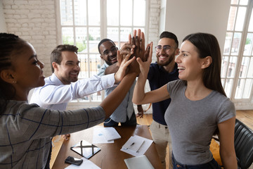 Excited diverse employee give high five at office meeting