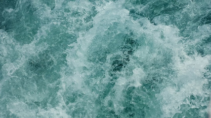 Fototapeta na wymiar speed tourist motorboat sails in emerald sea making white foamy trace waves close view