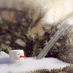 melting snowman under and a thermometer in a snowdrift under the sun in spring. oncoming of spring