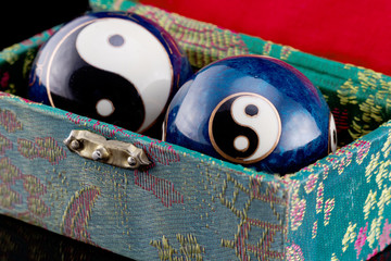 Blaue chinesische Klangkugeln mit Yin-Yang-Symbolen in einer mit grüner Seide bespannten Schachtel