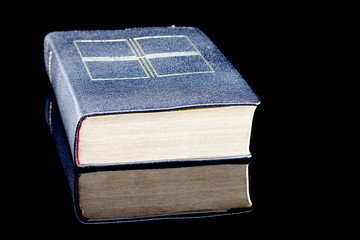 Katholisches Gesangbuch mit Goldschnitt und Spiegelung isoliert auf schwarzem Hintergrund