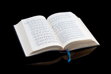 Aufgeschlagenes katholisches Gesangbuch mit Spiegelung isoliert auf schwarzem Hintergrund und Platz für Text