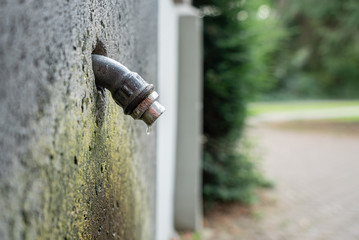 Tropfender Wasseranschluss der aus einer Mauer ragt
