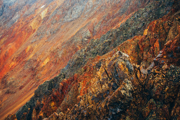 Vivid multicolor nature background of big rocky mountain with pointy rocks. Full frame surface of giant mountain rough wall close-up. Red orange yellow stones. Beautiful natural backdrop of rockies.