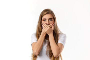 Portrait of young beautiful woman closes her mouth with hand on white background