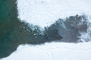 Aerial view of a blue and green lake with snow in winter in the Altai mountains in Russia. Nature and scenic spots.