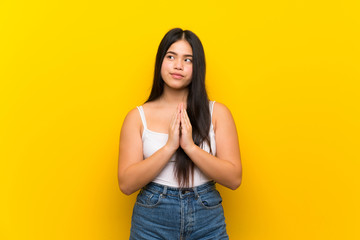 Young teenager Asian girl over isolated yellow background scheming something