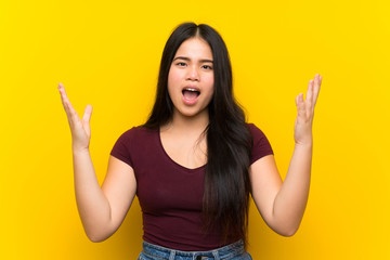 Young teenager Asian girl over isolated yellow background with surprise facial expression