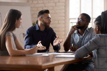 Thoughtful millennial diverse colleagues discuss ideas at briefing