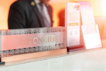 Concierge service desk counter with happy employee staff receptionist working in front of hotel with tourist guest business customer. - obrazy, fototapety, plakaty