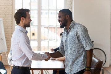 Diverse male employees handshake at office meeting