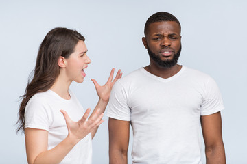 Furious young woman screaming at her annoyed black boyfriend