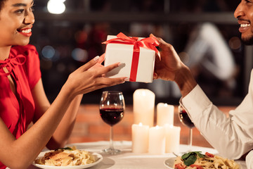 Loving Couple Exchanging Gifts Celebrating Valentine In Restaurant