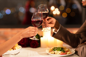 Couple's Hands Clinking Glasses Of Red Wine Dating In Restaurant