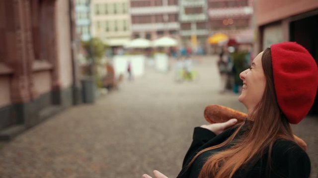 Two attractive French women in black jackets and berets compete evaluating each other the brunette beats the red haired woman with a loaf