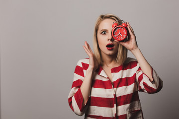 girl holds alarm clock on gray background