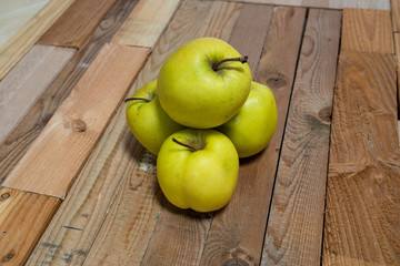 Green apples stacked and displayed on a rough wooden board as a background