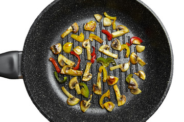 Cooking mushrooms with vegetables  in hot seed oil in a frying grill pan with non-stick coating, isolated on white background. Roasting colorful bell peppers with champignons, top view